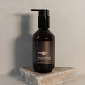 Black bottle labeled 'After Care' on a stone surface with a neutral background
