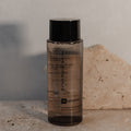 Skincare bottle labeled 'Synergie Skin' on a textured surface with a neutral background